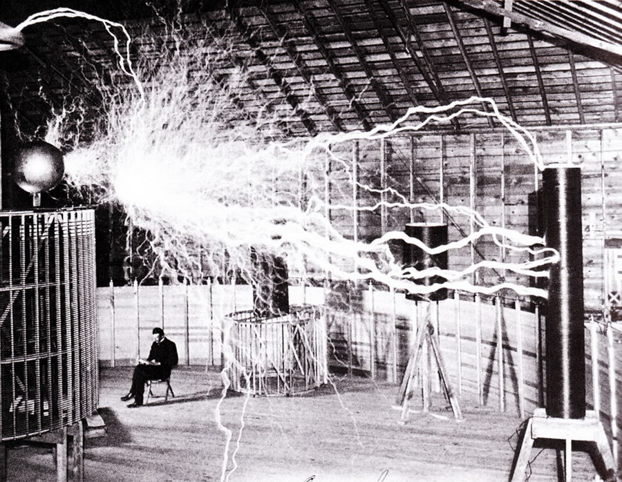 Tesla sitting in his laboratory with sparks